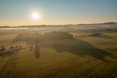 Tarım arazileri ve Alman köyüyle güneş doğarken insansız hava aracı görüntüsü.