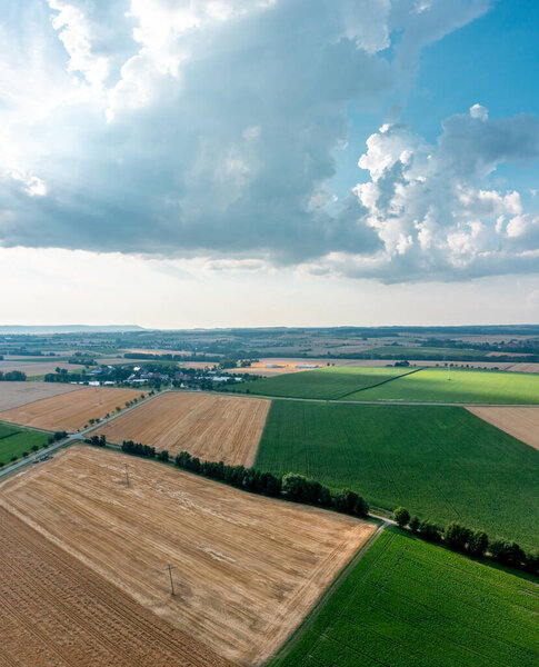 Вертикальная панорама беспилотника со многими сельскохозяйственными полями и голубым облачным небом.