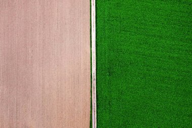 Almanya 'nın Baden Wurttemberg bölgesindeki iki tarım arazisi arasında kırsal bir yola sahip insansız hava aracı manzarası