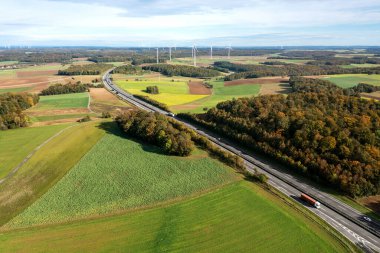 Ufukta iki şeritli otoyol ve rüzgar türbinleriyle sonbaharda insansız hava aracı görüntüsü