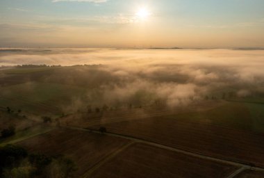 Almanya 'nın Schwabisch Hall şehrinde, sisle kaplı tarımsal manzaralarla dolu, altın saat sabahında insansız hava aracı görüntüsü