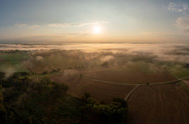 Almanya 'nın Schwabisch Hall şehrinde, sisle kaplı tarımsal manzaralarla dolu, altın saat sabahında insansız hava aracı görüntüsü