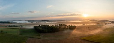 Almanya 'nın Schwabisch Hall kentindeki tarımsal tarlalar sisle kaplıyken, sabah havadan manzara manzarası