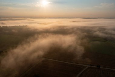 Almanya 'nın Schwabisch Hall kentindeki sisli tarımsal tarlalarla altın saatte güneşin doğuşu manzarası