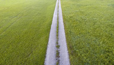 Güzel bir yaz gününde yeşil çim tarlalarından geçen kırsal bir yolu olan insansız hava aracı manzarası