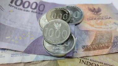 Metalden yapılmış bir yığın Endonezya parası ve beyaz arka planda kağıttan yapılmış bir tane.