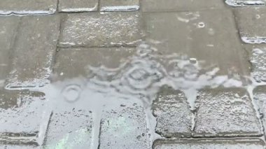 Öğleden sonra kaldırım taşlarına düşen yağmur suyu.