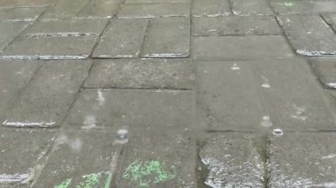 Öğleden sonra kaldırım taşlarına düşen yağmur suyu.