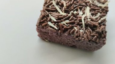 Bir parça çikolatalı ekmek, üzerine çikolata serpiştirilmiş beyaz arka planda rendelenmiş peynir.