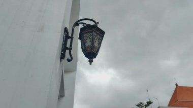 Duvara asılı antik bir lamba bulutlu bir gökyüzüne karşı süsleme olarak.