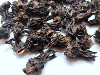 Arka planda kurumuş Roselle çiçekleri var. Kurumuş roselle çiçekleri gribi önlemek, ateş kaynaklı rahatsızlığı tedavi etmek ve antienflamatuar ve antibakteriyel özelliklere sahip olmak için faydalıdır..