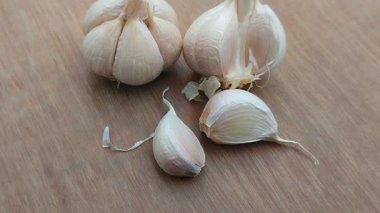 Ahşap arkaplanda sarımsak. Sarımsak (Allium sativum), özel bir tat ve aroması ve çeşitli sağlık faydaları olan popüler bir baharattır..