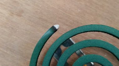 Ahşap desenli arka planda yanan bir çember şeklinde sivrisinek bobini.