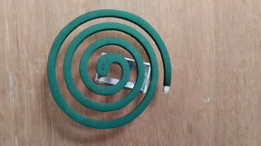 Ahşap desenli arka planda yanan bir çember şeklinde sivrisinek bobini.