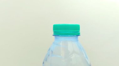 Beyaz arka planda plastik bir şişede su içmek