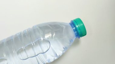 Beyaz arka planda plastik bir şişede su içmek
