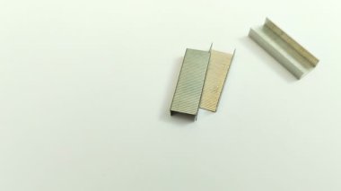 Beyaz arka planda bir sürü zımba var. Zımbanın içeriğine zımba denir ve işlevleri çeşitli medyayı birleştirmek veya bağlamak, genellikle kağıt.