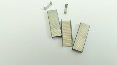 Beyaz arka planda bir sürü zımba var. Zımbanın içeriğine zımba denir ve işlevleri çeşitli medyayı birleştirmek veya bağlamak, genellikle kağıt.