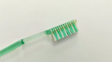 Beyaz arka planda yeşil ve beyaz diş fırçası. Oral sağlığınızı korumak için doğru diş fırçasını seçmeli ve doğru fırçalama tekniğini uygulamalısınız..