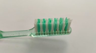 Beyaz arka planda yeşil ve beyaz diş fırçası. Oral sağlığınızı korumak için doğru diş fırçasını seçmeli ve doğru fırçalama tekniğini uygulamalısınız..