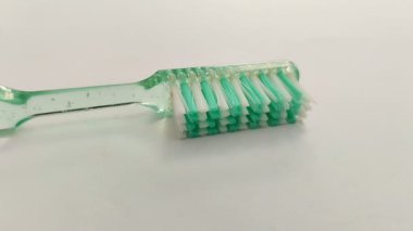 Beyaz arka planda yeşil ve beyaz diş fırçası. Oral sağlığınızı korumak için doğru diş fırçasını seçmeli ve doğru fırçalama tekniğini uygulamalısınız..