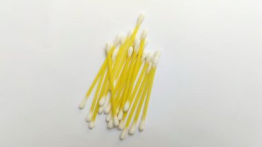 Beyaz arka planda bir yığın pamuk tomurcuğu. Bu kulak temizleme aracı genellikle kullanılır, ama yanlış kullanılırsa, enfeksiyon gibi sağlık sorunlarına neden olabilir veya kulak kirini daha derine itebilir.