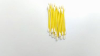 Beyaz arka planda bir yığın pamuk tomurcuğu. Bu kulak temizleme aracı genellikle kullanılır, ama yanlış kullanılırsa, enfeksiyon gibi sağlık sorunlarına neden olabilir veya kulak kirini daha derine itebilir.