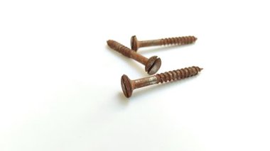 Beyaz arka planda paslı vida. Pas, demir, oksijen ve su arasındaki kimyasal etkileşimin bir sonucu olarak oluşur ve bu da metal yüzeyi aşındırır..