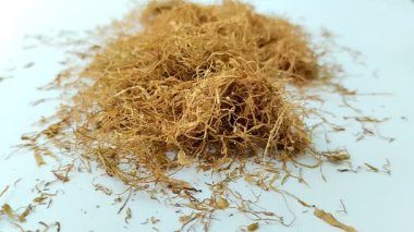 Beyaz arka planda kurumuş tütün yığını. Tütün, yaprakları sigara için hammadde olarak yaygın olarak kullanılan bir bitkidir.