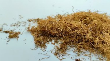 Beyaz arka planda kurumuş tütün yığını. Tütün, yaprakları sigara için hammadde olarak yaygın olarak kullanılan bir bitkidir.