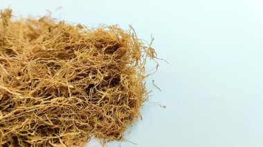 Beyaz arka planda kurumuş tütün yığını. Tütün, yaprakları sigara için hammadde olarak yaygın olarak kullanılan bir bitkidir.