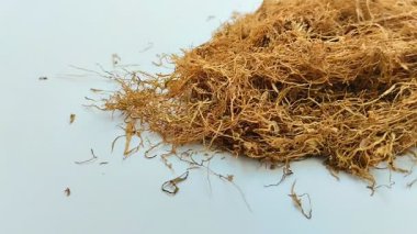 Beyaz arka planda kurumuş tütün yığını. Tütün, yaprakları sigara için hammadde olarak yaygın olarak kullanılan bir bitkidir.