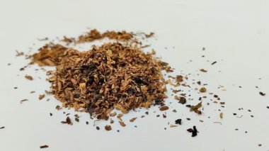 Beyaz arka planda kurumuş tütün yığını. Tütün, yaprakları sigara için hammadde olarak yaygın olarak kullanılan bir bitkidir..