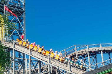 Helsinki, Finlandiya - 24 Haziran 2022: Lunaparktaki Linnanmaki gökyüzü arka planında bulanık hareket halinde hız trenine binin