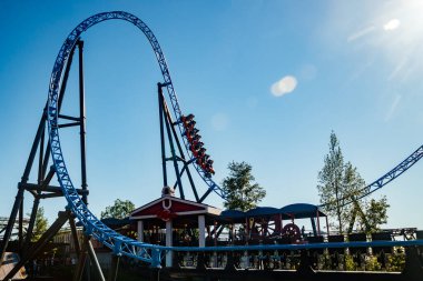 Helsinki, Finlandiya - 24 Haziran 2022: Lunaparktaki Linnanmaki gökyüzü arka planında bulanık hareket halinde hız trenine binin