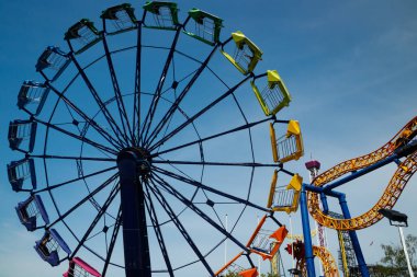 Gökyüzü arka planındaki eğlence parkında hareketli renkli yolculuklar.