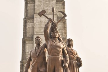 Kuzey Kore 'nin çekiç, orak ve kaligrafi fırçasını tutan üç kişinin olduğu bir heykel.