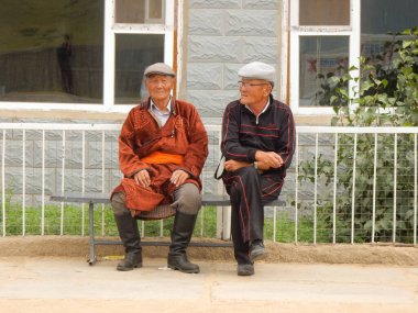 Testserleg, Mongolia - August 25 2016: Two elderly men sit and chat by the roadside in rural Mongolia clipart