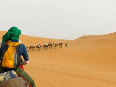 26 Şubat 2024 - Sahra Çölü, Fas: Turistler Fas 'taki Sahra Çölü' nün turuncu kumullarında deveye biniyorlar.
