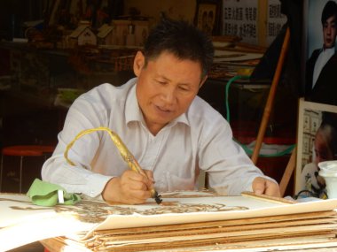 Luoyang, Henan Eyaleti, Çin - 29 Eylül 2016: Eski Kentte geleneksel Çin ahşap hediyeler oyan bir adam.