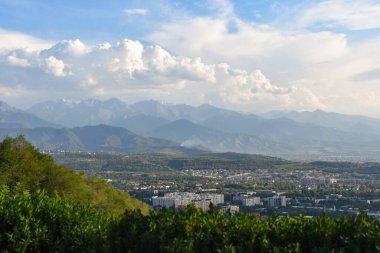 Almaty 'nin yüksek irtifa görüntüsü Tien Shan' ın eteklerindeki geniş şehir manzarasını, ana yolları ve yeşil bölgeleri gösteriyor..