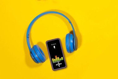 Podcast arka planı. Podcast uygulamalı mobil akıllı telefon ekranı, ses kulaklıkları