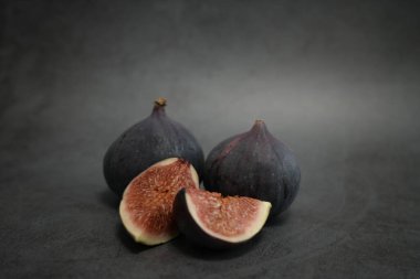 Lezzetli incirler dikkatlice kesilerek açılmış, parlak iç organlarını koyu bir arka plana karşı güzelce sergilemişlerdir.