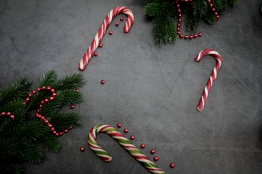 Şeker kamışları ve neşeli dekorasyonlar tatil temalı medya için karanlık bir yüzeye güzelce yerleştirilmiş.