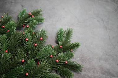Koyu bir arka planda parlak kırmızı süslemeleri olan bir Noel ağacı dalına yakın çekim. Tatil sezonu için mükemmel. Mesaj için yer. Üst görünüm.