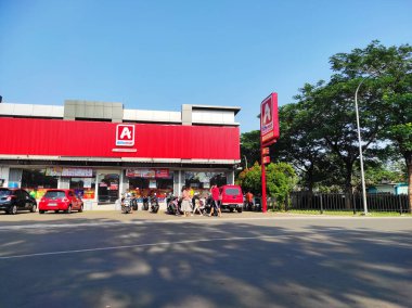 Ciledig, Endonezya - 15 Eylül 2024: Cesur kırmızı dış görünüşlü bir Alfamidi marketinin parlak ve net bir görüntüsü. Birçok motosiklet ve araba mağazanın önünde park edilmiştir.