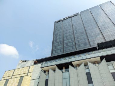 Hilton Oteli 'nin yanındaki parlak, açık mavi gökyüzünün altında parlak, modern bir DoubleTree cephesi.