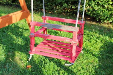 Parktaki oyun parkında eski bir ahşap kırmızı salıncak