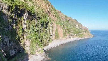 Küçük bir adası ve önü deniz olan kayalık bir uçurumun insansız hava aracı görüntüsü. Okyanus Madeira. Portekiz.