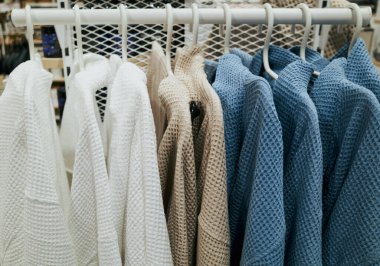 Ortasında mavi-beyaz ceket olan bir sürü kıyafet. Askı kıyafetlerle dolu ve sadece mavi ceket beyaz değil.